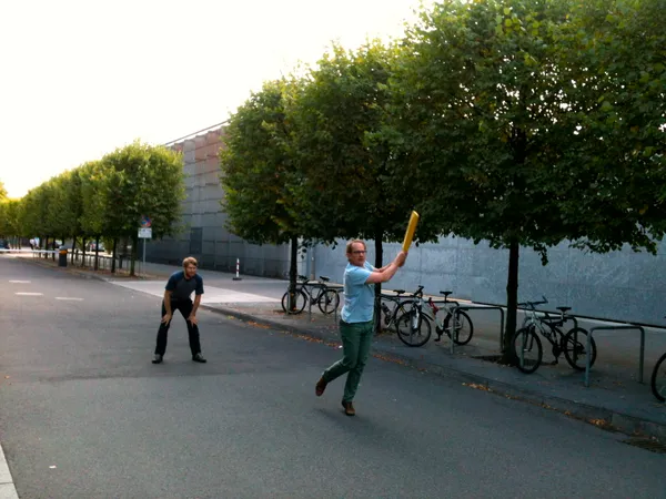 Two men playing cricket in a parking lot