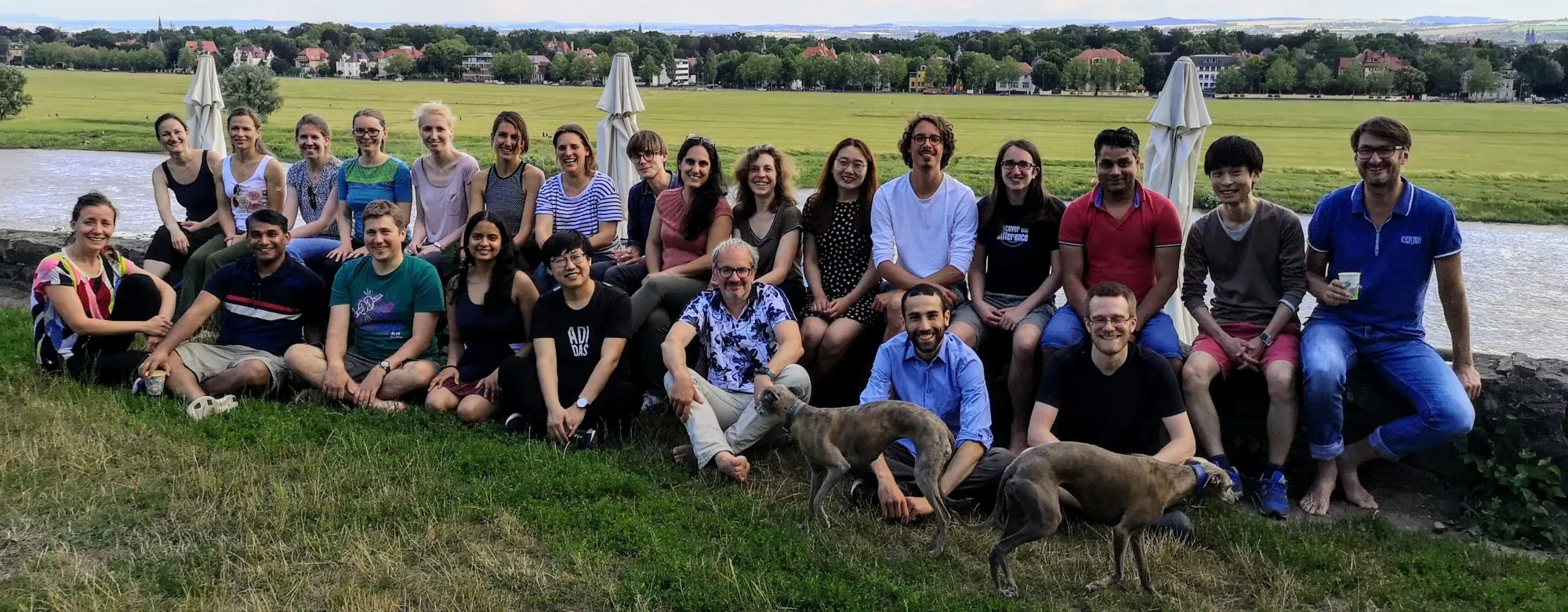 The Hyman lab members smile on a grassy river bank